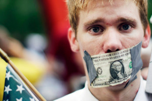 A demonstrator from the Occupy Wall Street campaign stands with a dollar taped over his mouth in Zucotti Park near the financial district of New York